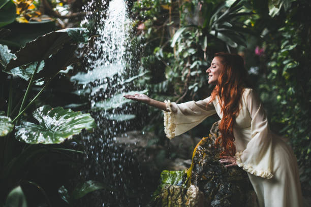 Woman in white dress standing against waterfall