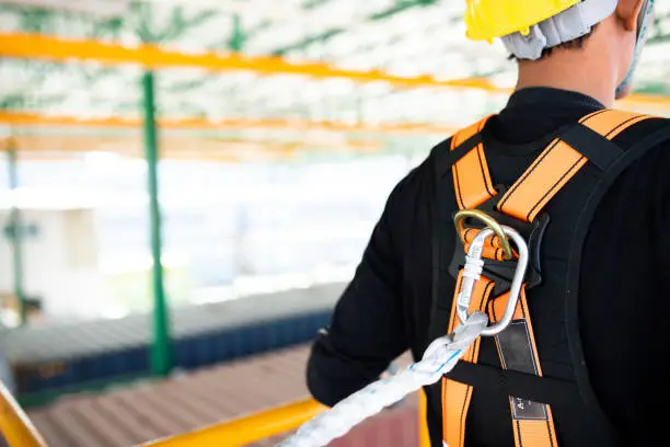 Photo of Construction worker wearing safety harness and safety line working on construction