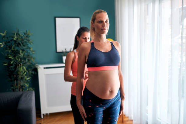 istock Pregnant woman exercising with instructor 1054423688