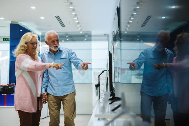 istock Beautiful senior couple at tech store. Looking for a new TV. 1054443622