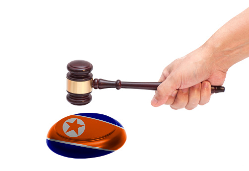 Hand knocking a Judge gavel at soundboard with Flag of North Korea Isolated on white background