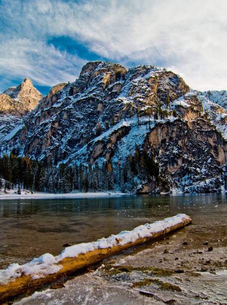 istock snowy log in mountain lake with mountains and blue sky 1054486776
