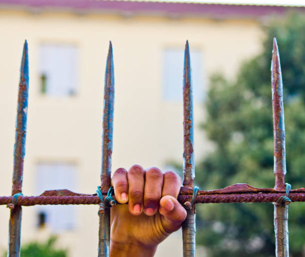 istock hand of a convict inside a prison 1054500356