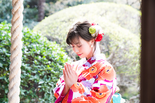 Mujer asiática atractiva usando kimono japonés rezando en un santuario sintoísta. photo