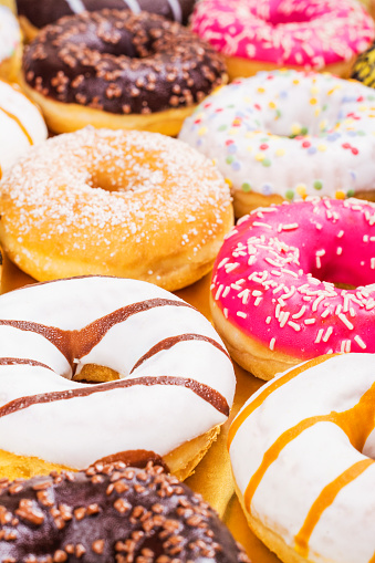 Assortment of colorful donuts on golden background. Party, birthday celebration food. Selective focus