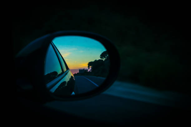 istock Right mirror driving car on an orange sunset landscape 1054580476
