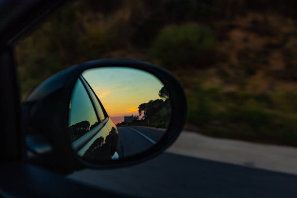 istock Right mirror driving car on an orange sunset landscape 1054580506