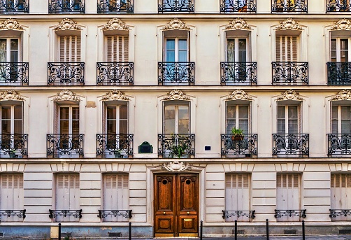 Street view of the elegant facade of an old apartment building in a residential neighborhood of Paris. Vintage style photo.