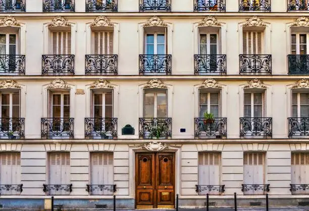 Photo of Street view of the elegant facade of an old apartment building in a residential neighborhood of Paris. Vintage style photo.
