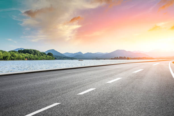istock Asphalt road and beautiful mountain with lake at sunset 1054589146