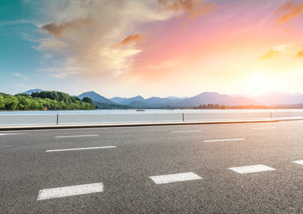 istock Asphalt road and beautiful mountain with lake at sunset 1054589766