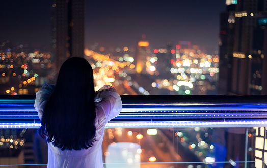 Woman enjoying with night city view from the balcony