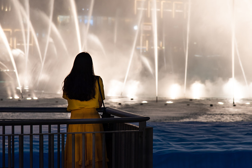 Woman with Dubai mall fountain show view at night