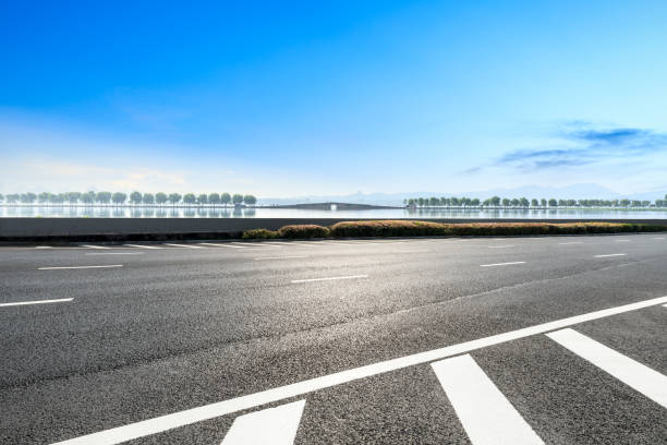 istock Asphalt road and beautiful trees with lake under the blue sky 1054596644