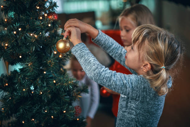 decorare l'albero di natale con ornamenti e luci di natale - christmas family child christmas tree foto e immagini stock