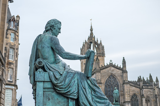 David Hume Statue with St. Giles Cathedral on the background on Royal Mile in Edinburgh, Scotland