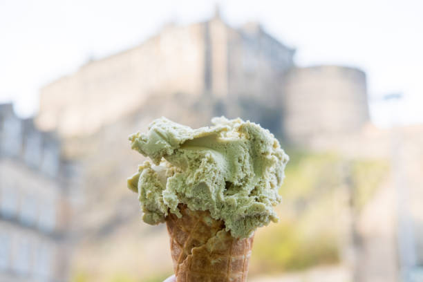 рука, держащая фисташковый gelato, мороженое с размытым фоном эдинбургского замка. - melting ice cream cone chocolate frozen стоковые фото и изображения
