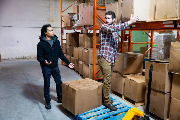 istock A warehouse employee working unsafely by standing on a pallet that's on a pallet jack 1054623824