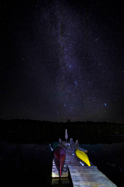 istock Boat dock under a starry sky as meteor streaks across the Milky Way 1054642068