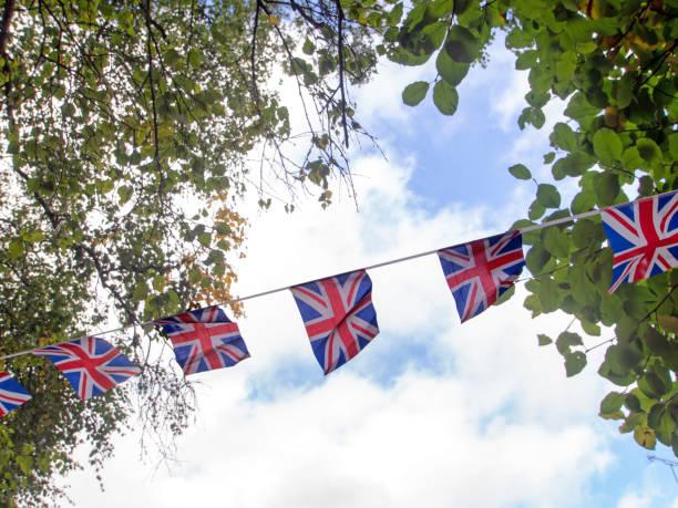 istock Red, white and blue festive bunting flags against sky background. Union Jack, UK flags blowing in the wind. 1054649820