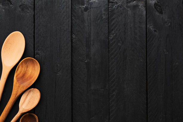 Wooden spoons on black wooden background.