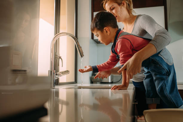 Little boy with mother washing hands in kitchen sink Little boy with mother washing hands in kitchen sink. Woman helping her son to wash hands in kitchen sink after cooking. kitchen sink stock pictures, royalty-free photos & images