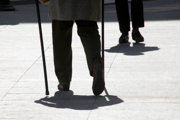 istock Two people walking, backlit, one with walking canes. 1054662770