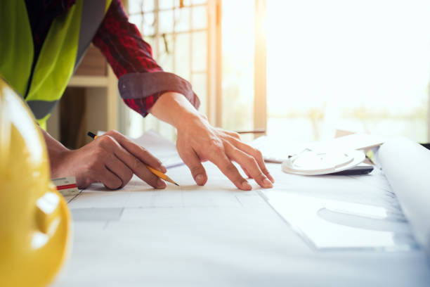 istock Close up of engineer hand drawing plan a construction project with pencil compass. 1054663226