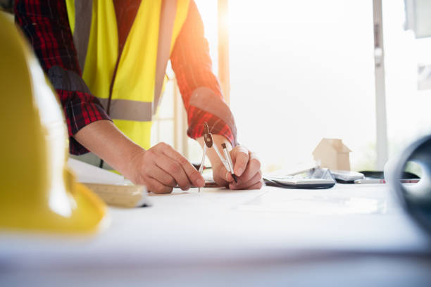 istock Close up of engineer hand drawing plan a construction project with pencil compass. 1054663238
