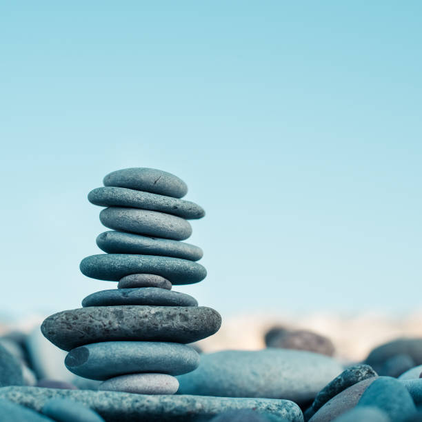 istock Stone cairn on green blurry background, pebbles and stones. Concept balance 1054663380