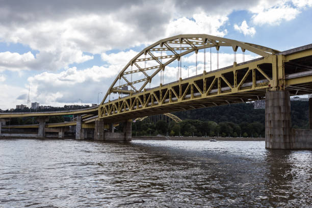istock Yellow bridge crossing large river into urban area 1054673710