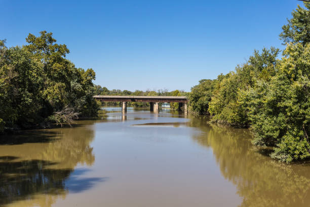 lodoso río que fluye bajo el puente viejo - red river fotografías e imágenes de stock
