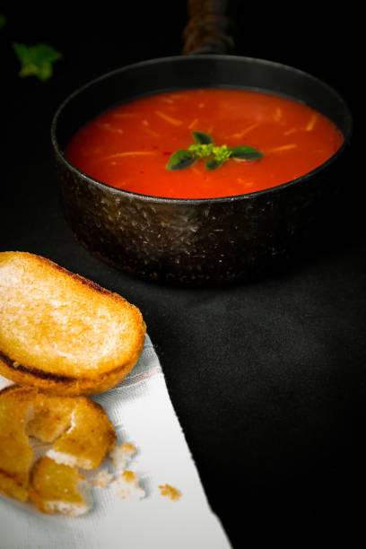 istock Tomato Soup with croutons and basil on black background 1054683296