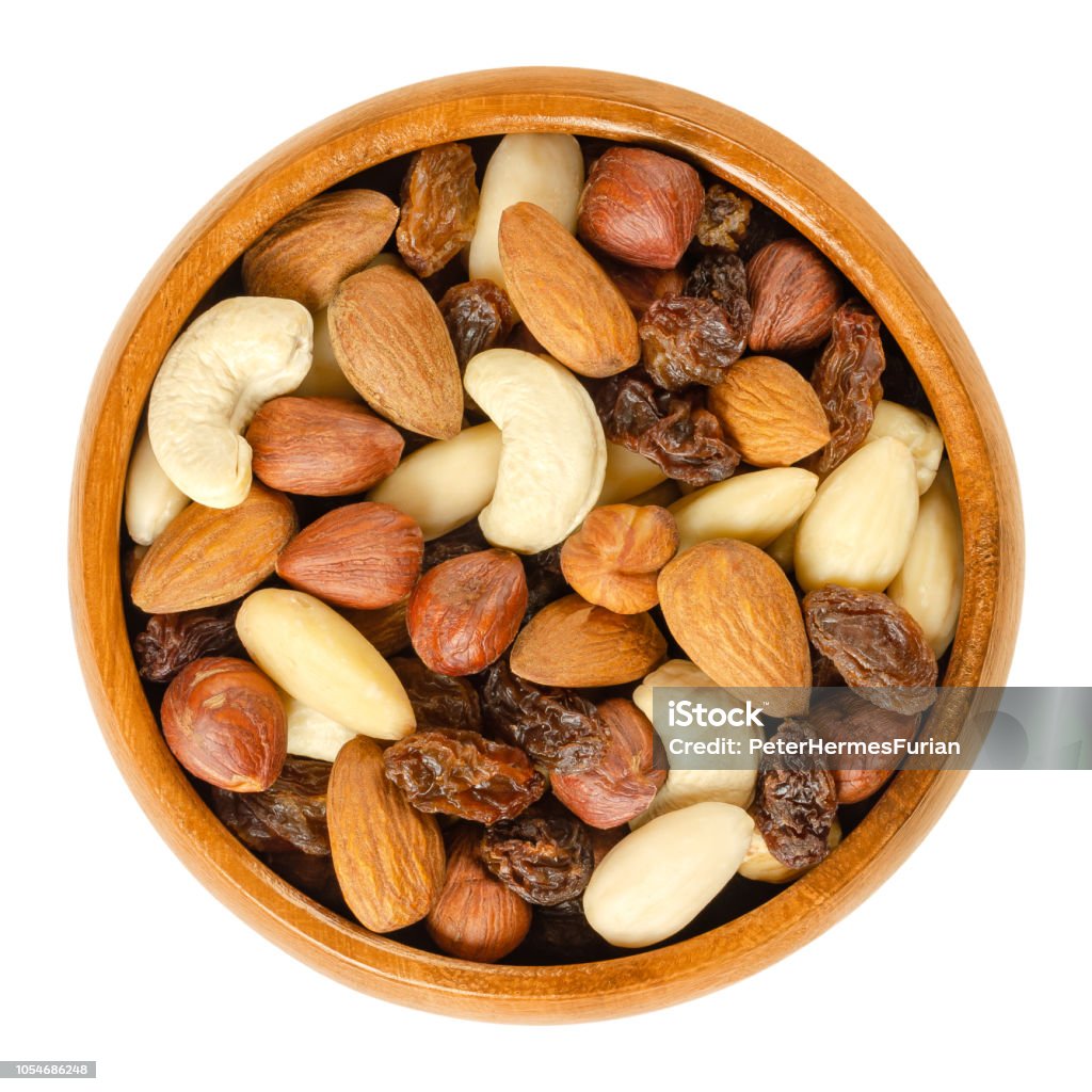 Nuts and raisins in wooden bowl over white Nuts and raisins in wooden bowl. Snack mix of dried almonds, hazelnuts, cashews and raisins.
Trail mix. Edible, raw, organic and vegan. Isolated macro food photo closeup from above on white background Nut - Food Stock Photo