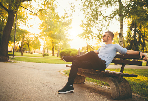 Young man sitting on bench in a park and relaxing