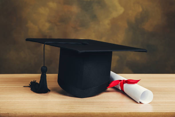 istock Graduation concept.graduation cap, hat with degree paper on wood table. 1054686786