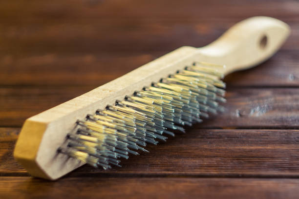 Wire brush is staying down on a brown wooden boards