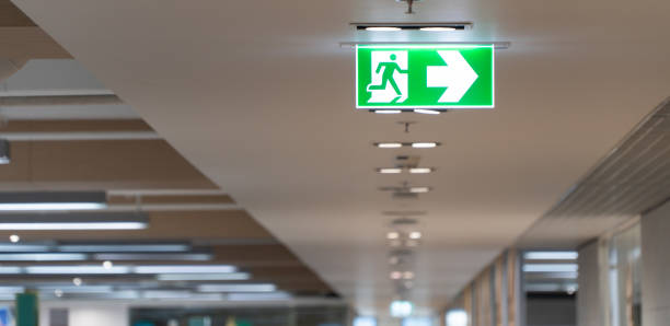 istock Green fire escape sign hang on the ceiling in the office. 1054692494