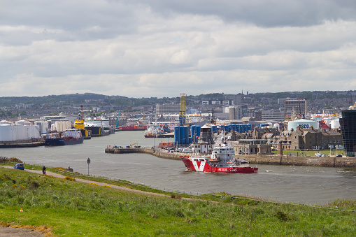 Aberdeen, UK - May 2016: A view from Nigg Bay in Aberdeen, looking over Aberdeen Harbour, with an offshore supply vessel in the foreground entering the harbour.