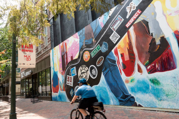 A security man biking past a mural in downtown Memphis Memphis, USA - August 12, 2018. A security man biking past a mural in downtown Memphis, a city on Mississippi River in the state of Tennessee and rich in history in American music cultures. memphis tennessee stock pictures, royalty-free photos & images