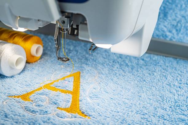 Embroidery machine and monogram logo design Close up image yellow a alphabet design on blue towel in hoop of embroidery machine machine sewing white sewing item stock pictures, royalty-free photos & images