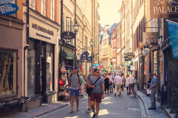 Tourists walking the historical streets of Gamla Stan, the old town of Stockholm, Sweden. Pictured here is Västerlånggatan, one of the main streets offering a variety of stores, cafes and restaurants.
