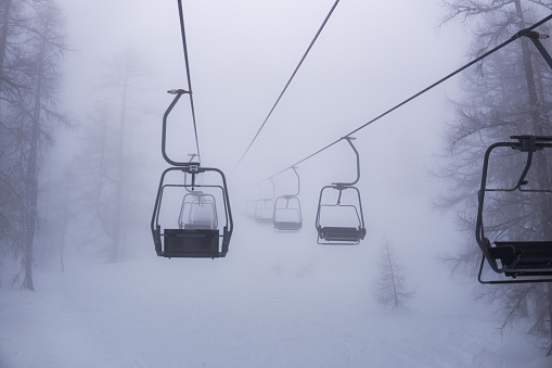 empty ski lift in fog, foggy skiing conditions, skiing in the beautiful alps of Austria, winter season theme image, endless chair lift