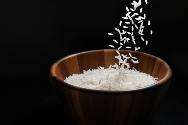 istock Pouring jasmine rice into a wooden bowl on black background 1054704992