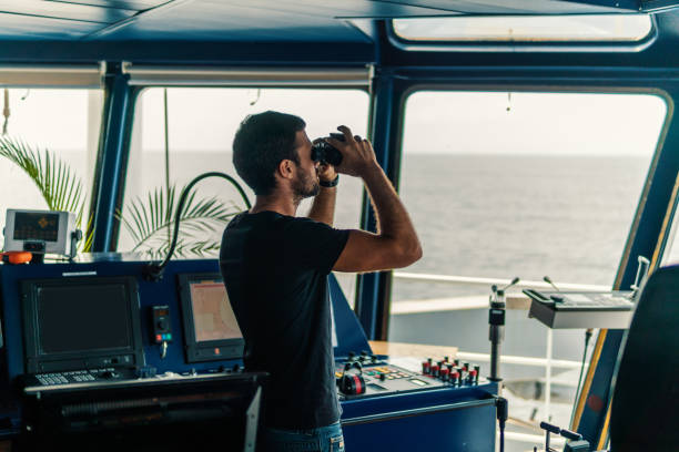 istock Navigational officer lookout on navigation watch looking through binoculars 1054705530