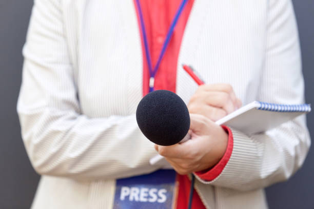 istock Female journalist at news conference, writing notes, holding microphone 1054705996