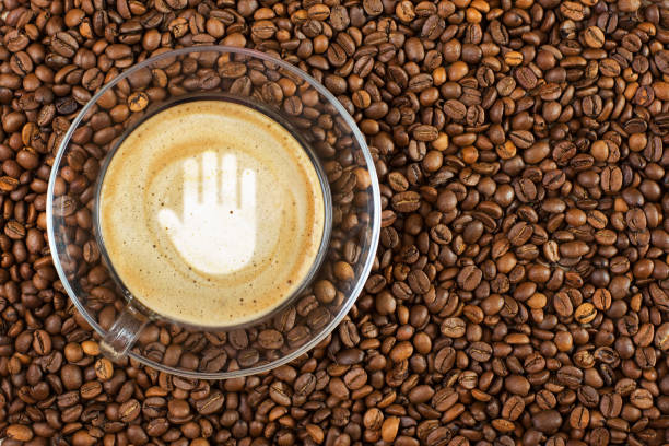 Cup of espresso with stop gesture sign on coffee foam on coffee beans background. With copy space stock photo