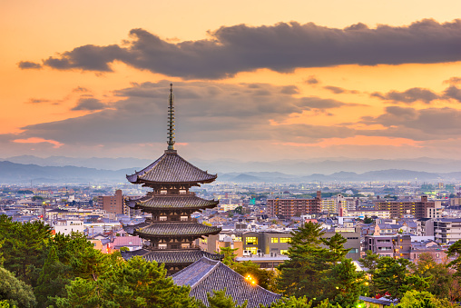 Nara, Japan - November 27, 2015: The five-story pagoda of Kofuku-ji Temple stands against the downtown cityscape of Nara Japan at dusk. The temple dates from the year 669.