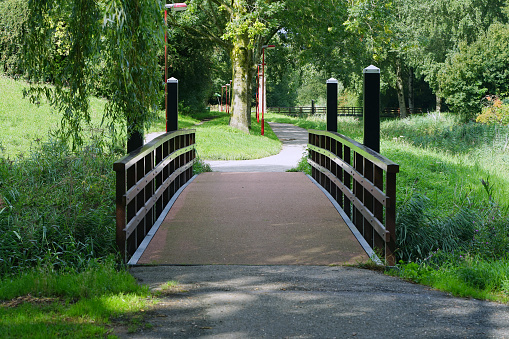 Wooden bridge over little river in city park. Little arched wooden bridge over garden pond. Arched wooden bridge over the pond. A small wooden bridge over the forest source with clean, cool water.