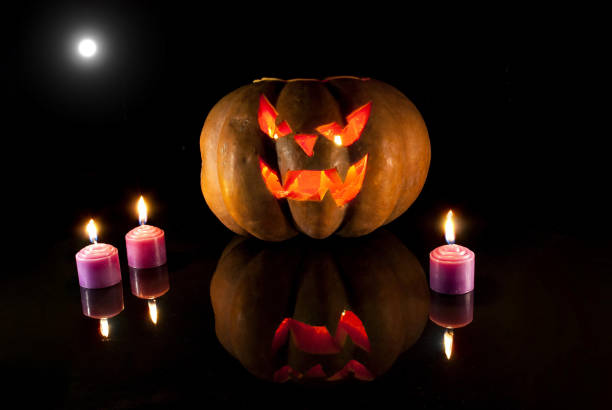 istock Halloween carved pumpkin and candle on black background with moon 1054735152